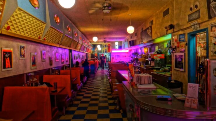 Retro diner interior with booths, neon lights, and a checkered floor
