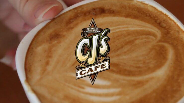 Close-up coffee cup with the CJ’s Café logo over latte foam