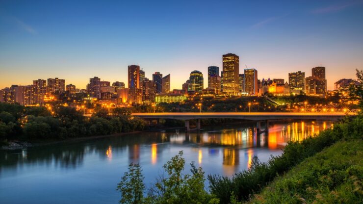 Edmonton skyline at dusk with city lights reflecting on the North Saskatchewan River