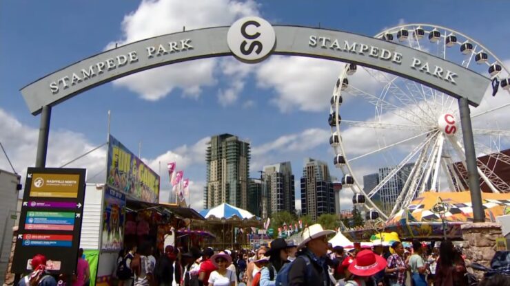Crowds walk beneath the Stampede Park entrance beside the Ferris wheel in Calgary